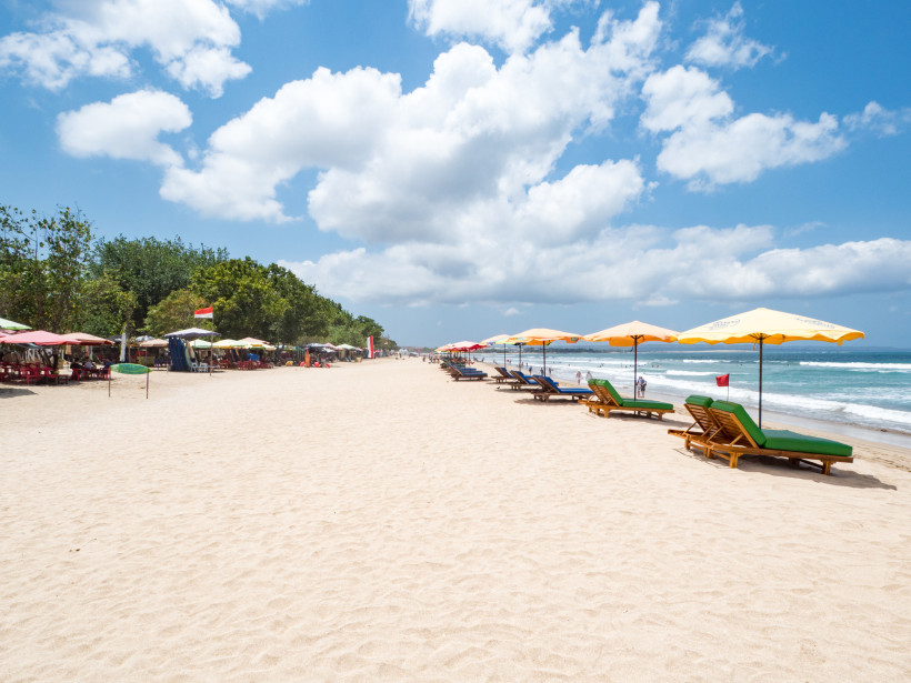 Seminyak, Bali Weißer Sandstrand mit bunten Sonnenschirmen und Sonnenliegen am Kuta Beach auf Bali