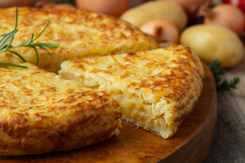Spanische Tortilla mit Kartoffeln, angeschnitten auf einem Holzbrett