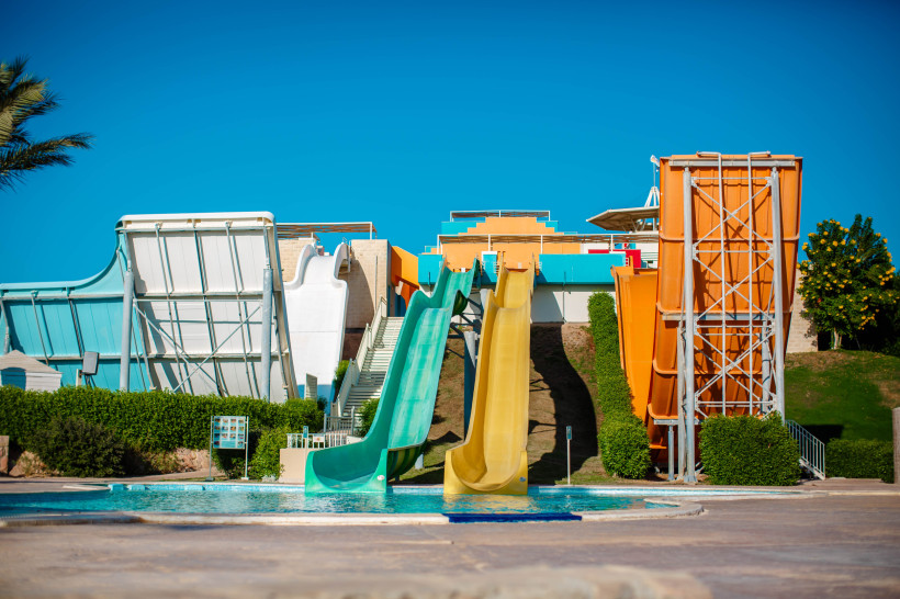 Wasserrutschen im Aquapark einer Ferienanlage Mehrere bunte Wasserrutschen in einem Aquapark, die in einen Pool führen