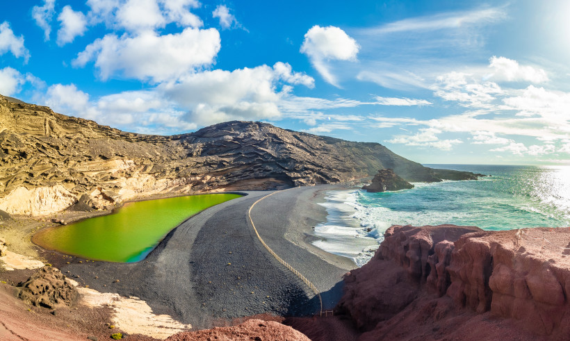 Panoramablick auf den Lago Verde in El Golfo auf Lanzarote mit leuchtend grüner Lagune, schwarzem Lavastrand und bizarren Felsformationen am Atlantik.