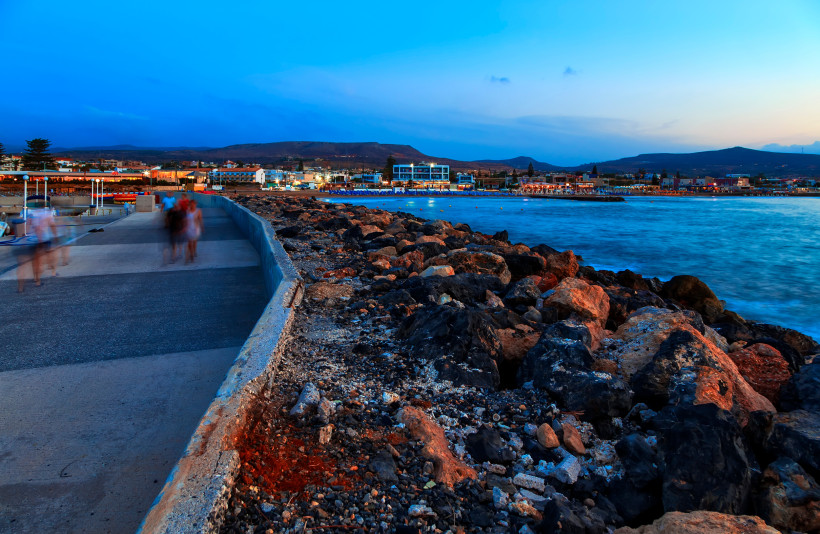 Promenade in Kato Gouves am Meer mit Felsufer und Küstenbebauung in der Abenddämmerung