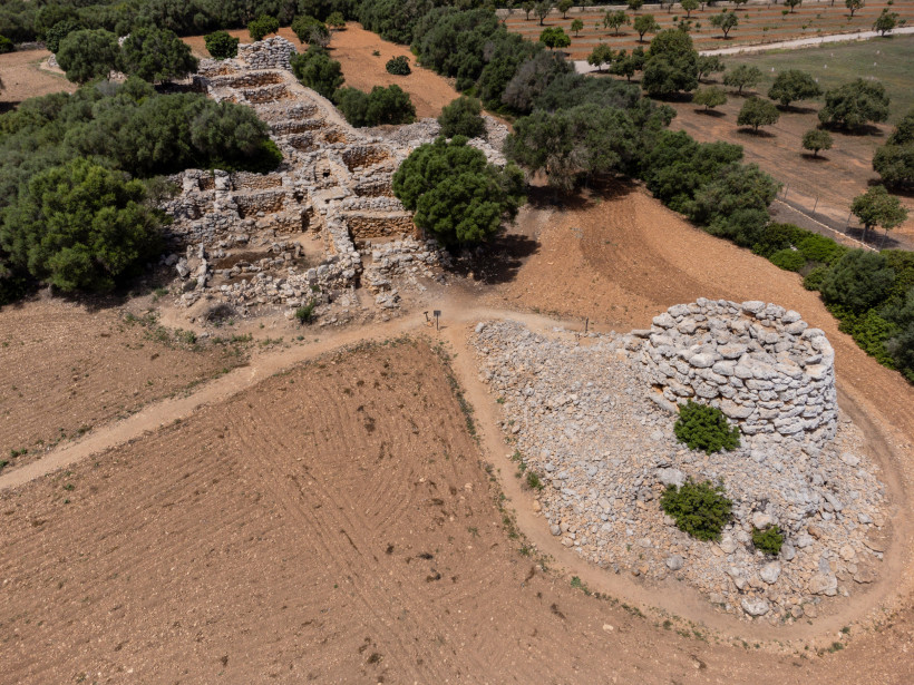 Luftaufnahme der prähistorischen Ruinenanlage Capocorb Vell mit steinernen Rundbauten und Trockenmauern in einer ländlichen Landschaft