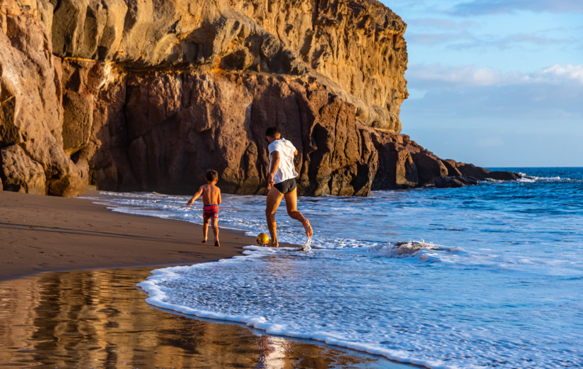 Gran Canaria Ein Kind und sein Vater spielen Fußball am Strand.