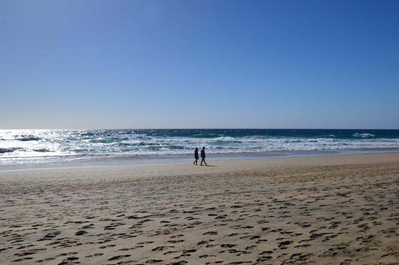 Sandstrand und Brandung bei Morro Jable, zwei Personen am Wasser