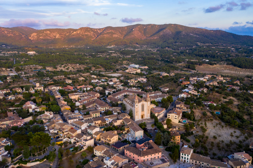 Calvia Dorf im Südwesten Mallorcas – Historischer Ortskern im Tramuntana-Vorland Luftaufnahme von Calvia Dorf mit Kirche Sant Joan Baptista, Natursteinhäusern und ländlicher Umgebung vor der Bergkulisse im Westen Mallorcas.