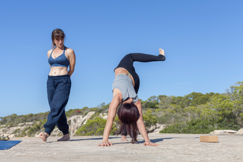 Yogaunterricht im Freien auf Mallorca: zwei Personen, eine in einer Handstand-Übung