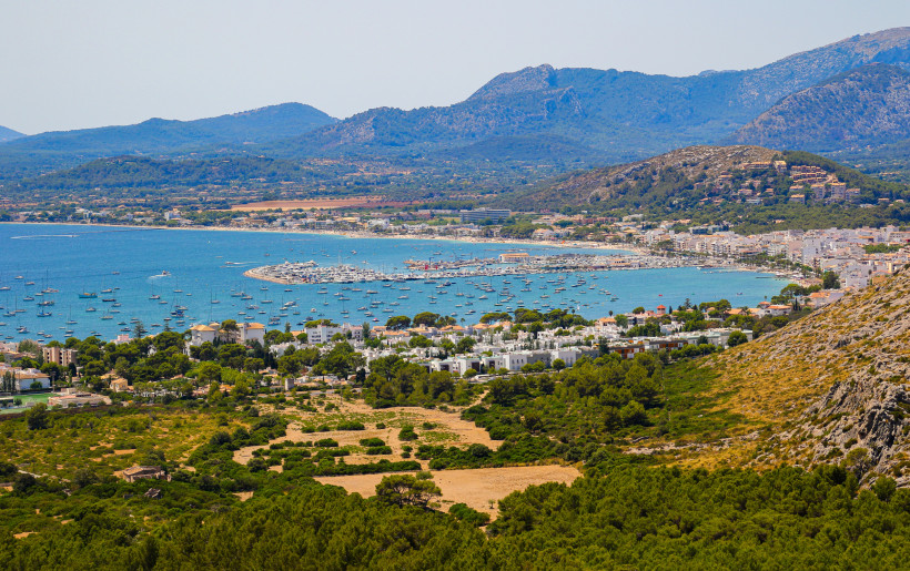 Mallorca - Port de Pollença Panoramablick auf Port de Pollença im Norden Mallorcas. Zahlreiche Segelboote und Yachten liegen in der Bucht vor Anker, während im Hintergrund die imposante Serra de Tramuntana das Bild bestimmt. Die Stadt liegt eingebettet zwischen Hügeln und dem türkis