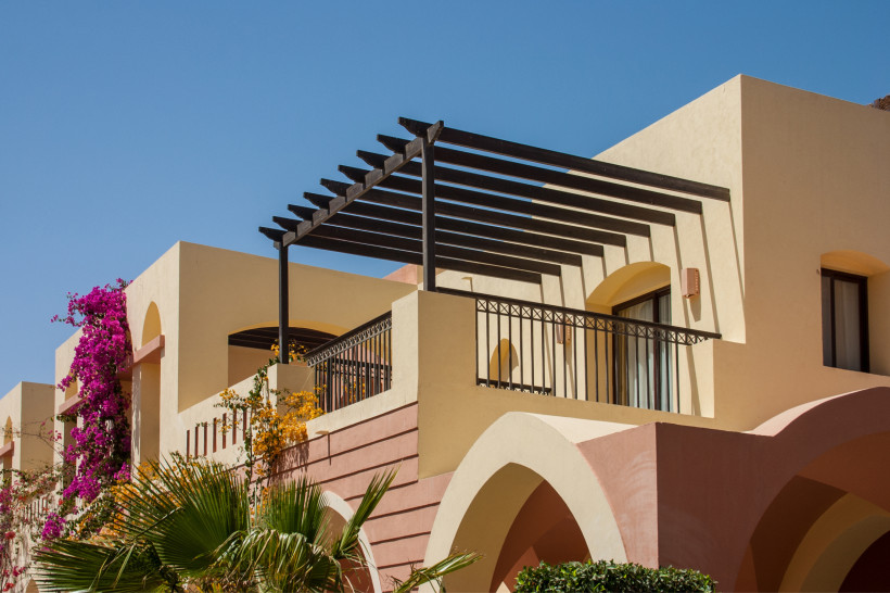 Exklusive Hotelterrasse in Ägypten – Urlaub mit Stil und mediterranem Flair Moderne Hotelterrasse mit Holzpergola, rosa Bougainvillea und klarblauem Himmel