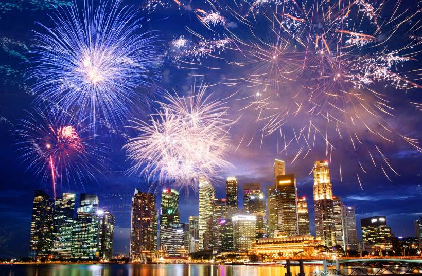 Singapur Feuerwerk über der nächtlichen Skyline von Singapur mit ihren glitzernden Hochhäusern. Die farbenfrohen Lichter des Feuerwerks spiegeln sich im Wasser und schaffen eine festliche Atmosphäre