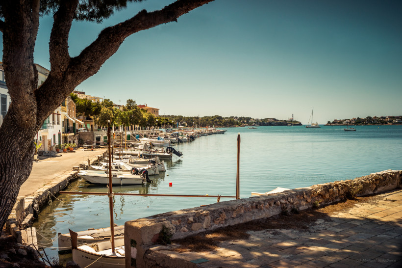 Hafenpromenade mit kleinen Booten und Segelbooten in Portocolom, Mallorca