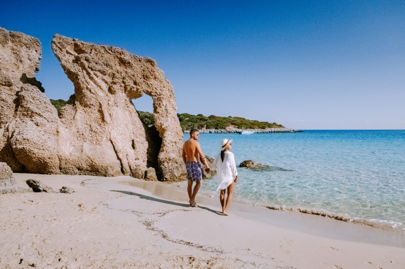 Voulisma Beach: Sandstrand und Felsformation an der Küste Voulisma Beach mit Sandstrand, Felsformation und türkisblauem Meer, zwei Personen am Ufer
