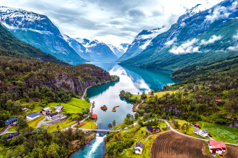 Norwegischer Fjord mit Berglandschaft, Uferstraße und Häusern Fjord in Norwegen mit türkisfarbenem Wasser, umliegenden Bergen und kleinen Siedlungen am Ufer