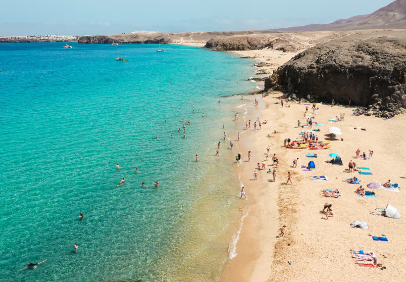 Papagayo-Strände auf Lanzarote – Baden im kristallklaren Atlantik Badegäste am hellen Sandstrand der Papagayo-Strände auf Lanzarote, mit klarem türkisfarbenem Wasser und vulkanischer Felsküste.