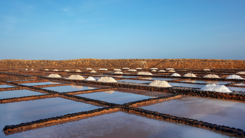 Salinas del Carmen mit rechteckigen Salzbecken und weißen Salzbergen unter blauem Himmel