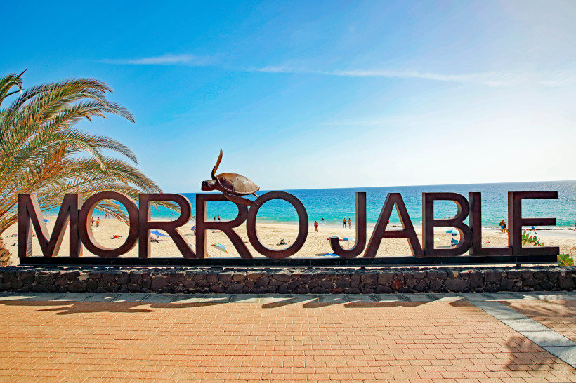 Schriftzug „Morro Jable“ an der Strandpromenade mit Blick auf den Strand und das Meer in Jandía
