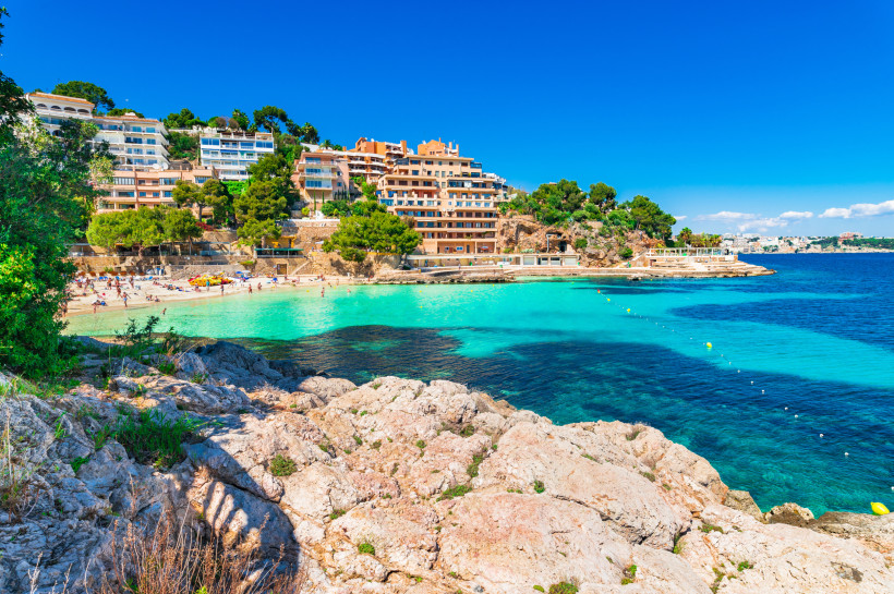 Kleine Badebucht in Illetes bei Calvia mit türkisblauem Wasser und Hotels oberhalb der Felsen