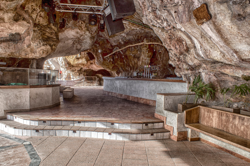 Menorca - Cova d’en Xoroi Innenansicht der Cova d'en Xoroi auf Menorca: eine Bar mit Tischen und Theke, eingebettet in die natürlichen Felsen einer großen Höhle.