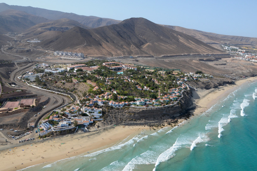Esquinzo auf Fuerteventura – Ruhe, Naturkulisse und goldene Strände Luftaufnahme von Esquinzo auf Fuerteventura mit Hotels auf dem Felsplateau, goldenem Sandstrand und türkisfarbenem Meer