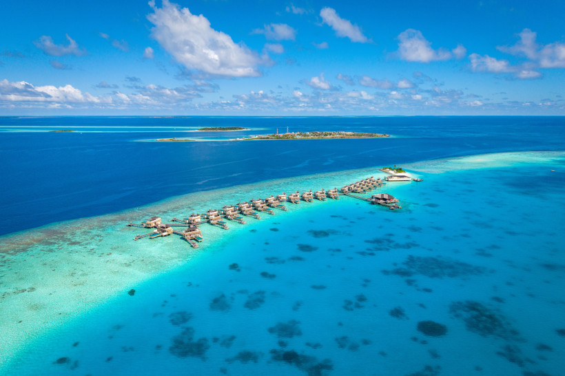 Luftaufnahme von Wasserbungalows in türkisblauer Lagune im Dhaalu-Atoll