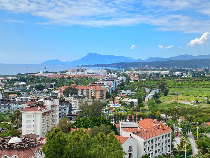 Günstiger Urlaub in Antalya – preiswerte Ferien an der Türkischen Riviera Panoramablick auf Antalya mit Hotels, Grünflächen, Meer und Bergen im Hintergrund – Symbol für budgetfreundlichen Urlaub, günstiges Reisen und preiswerte Ferien in der Türkei