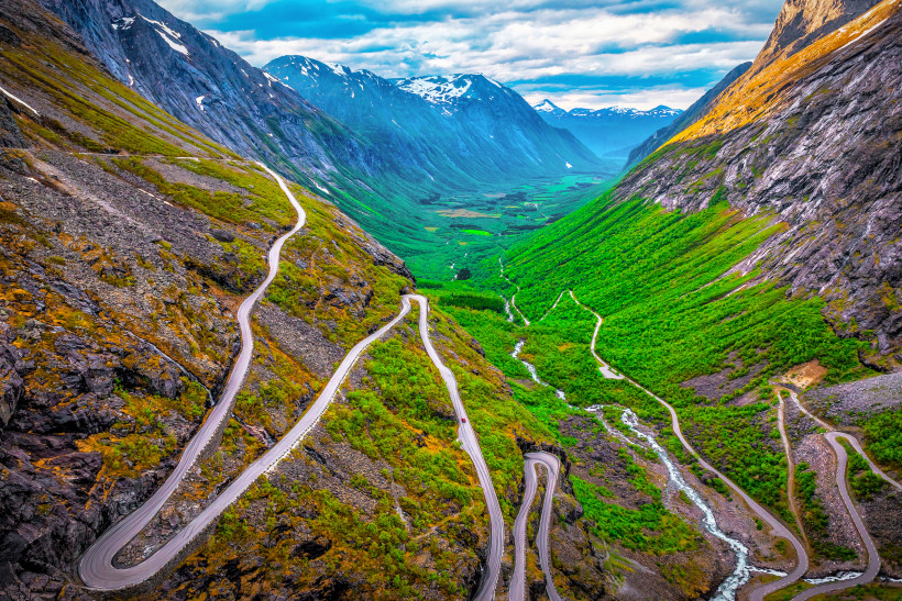 Trollstigen: Serpentinenstraße im Gebirge mit Blick ins Tal Trollstigen in Norwegen mit Serpentinenstraße durch steiles Gebirgstal und grünem Talboden