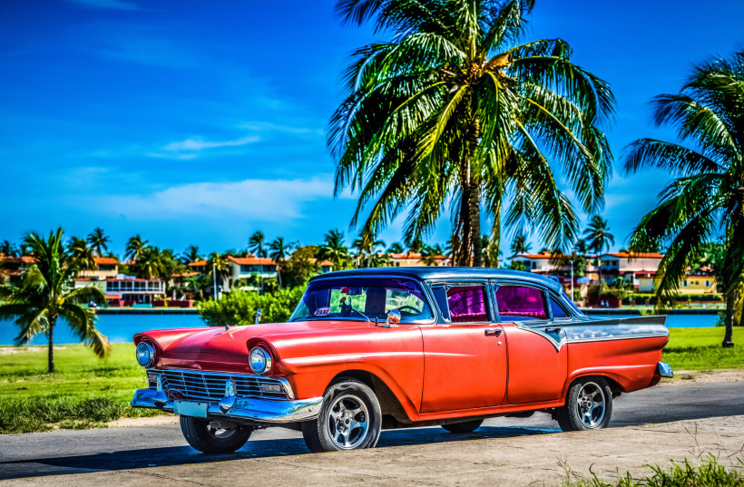 Roter amerikanischer Oldtimer aus den 1950er-Jahren vor Palmen und Lagune in Varadero auf Kuba – ikonisches Symbol der kubanischen Kultur und Lebensfreude.