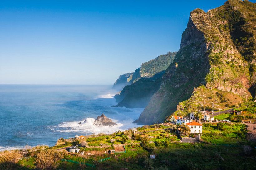 Madeira: Steilküste am Atlantik mit Felsen und Siedlung am Berghang Steilküste auf Madeira mit Atlantik, Felsen im Meer und Häusern am Hang