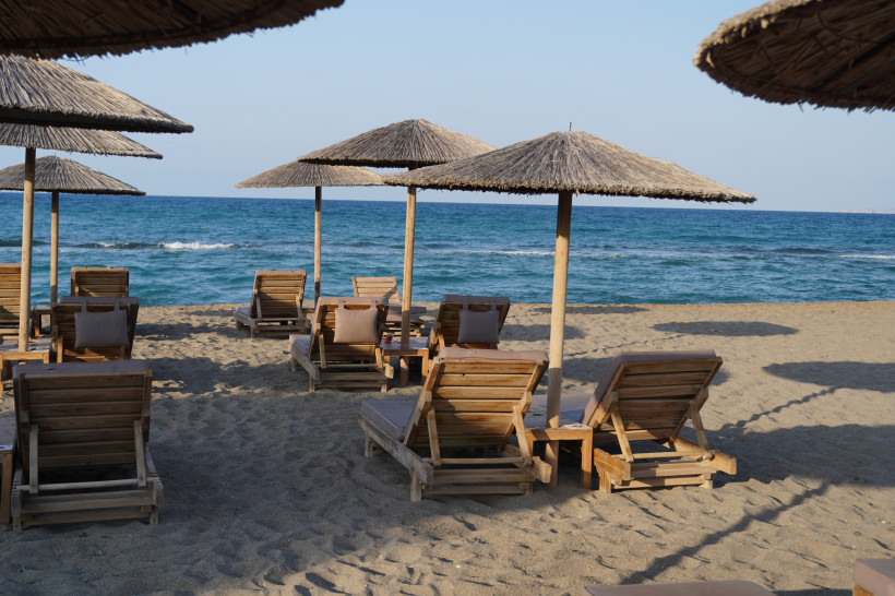 Strandliegen und Strohsonnenschirme am Amoudara Beach am Meer