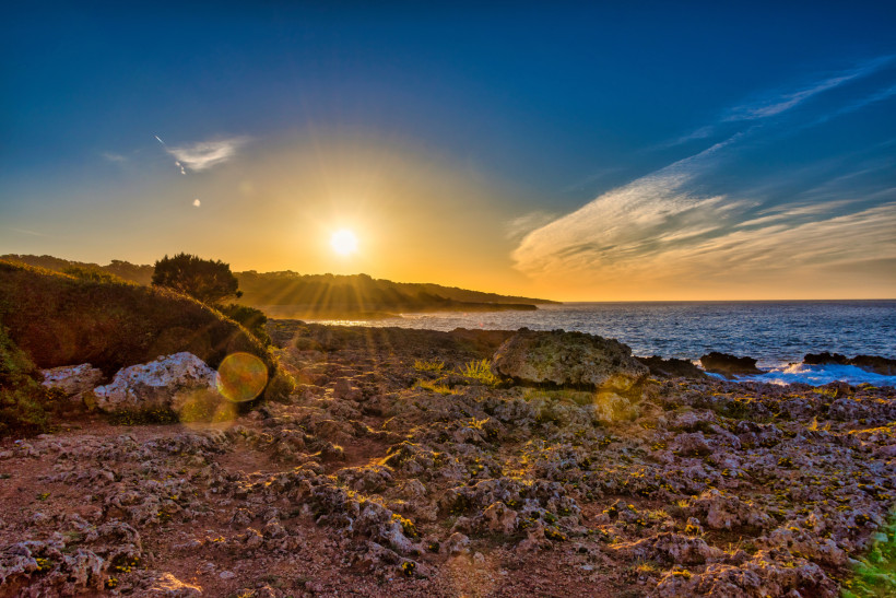 Sonnenuntergang an der Küste von Sa Coma mit Felsen und Meer