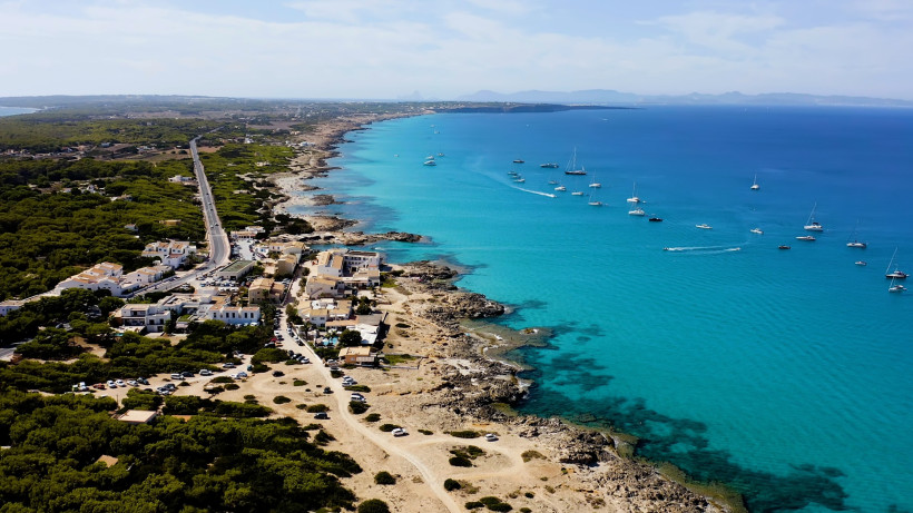 Luftaufnahme der Küste von Formentera mit türkisblauem Wasser, Booten und ursprünglicher Landschaft