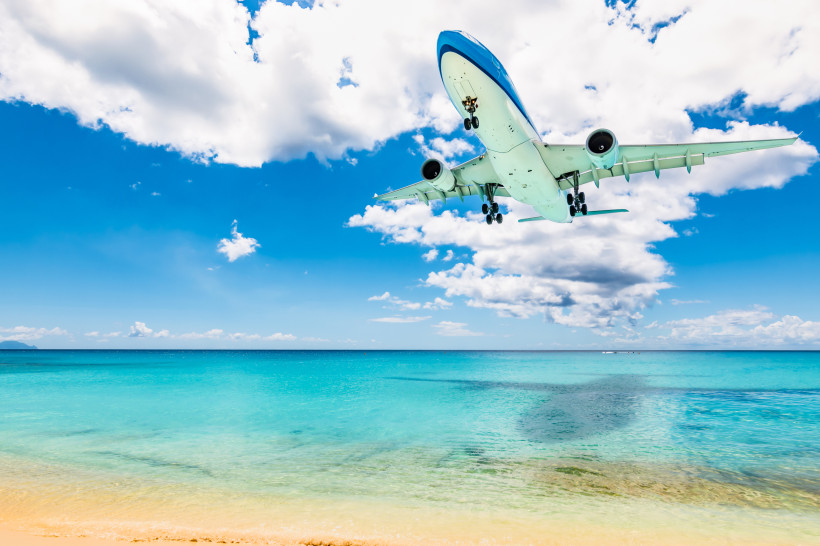 Tief fliegendes Passagierflugzeug über dem türkisfarbenen Meer am Maho Beach auf St. Maarten