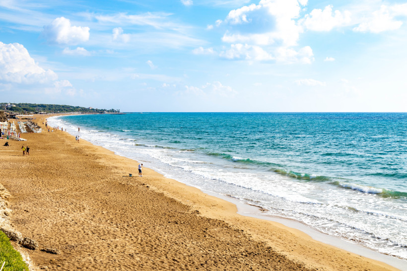 Breiter Sandstrand in Side mit sanften Wellen und Blick auf das Mittelmeer