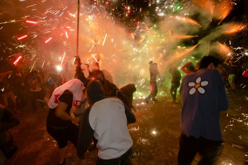 Mallorca Menschen tanzen und ducken sich inmitten eines spektakulären Funkenregens während eines Correfoc, eines traditionellen Feuerlaufs auf Mallorca. Pyrotechnische Effekte sprühen in alle Richtungen, es ist Nacht. Einige tragen Kapuzen oder haben sich mit Tüch