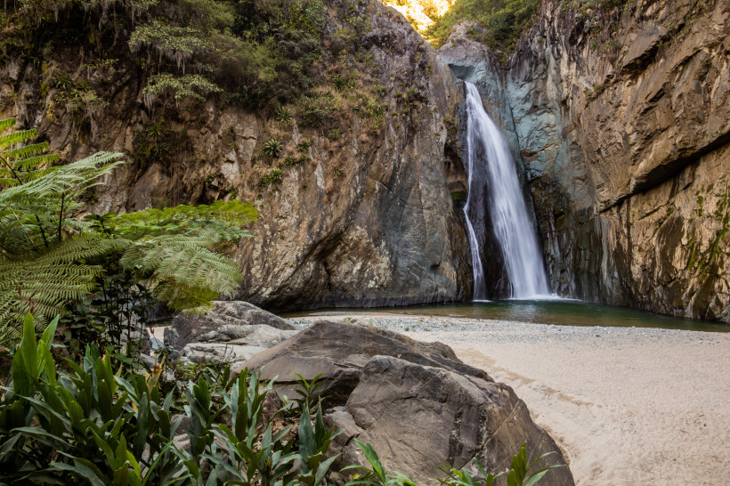 Jarabacoa, Dom.Rep. Beeindruckender Wasserfall inmitten einer Felsenschlucht in der Dominikanischen Republik, umgeben von üppiger Vegetation und Felsen