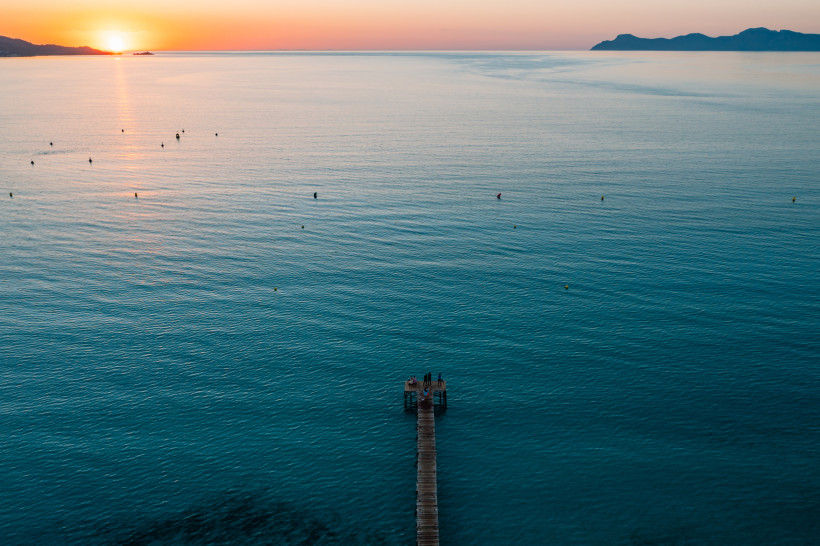 Steg in der Bucht von Alcudia bei Sonnenuntergang, ruhiges Meer und weite Aussicht – entspannte Abendmomente für Paare und Erwachsene