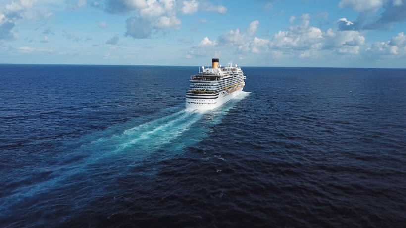 Kreuzfahrtschiff auf offenem Atlantik mit Heckwasser vor wolkigem Himmel