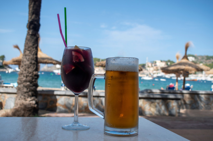 Erfrischende Auszeit am Strand Ein Glas Sangria und ein Bier stehen auf einem Tisch mit Meerblick und Strohdächern im Hintergrund – perfekter Moment für einen entspannten Nachmittag am Strand von Gran Canaria.