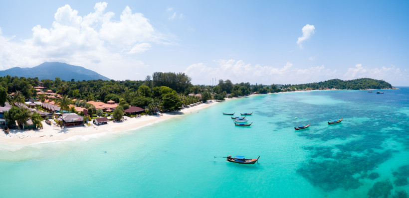 Ko Lipe im Frühling – Türkisblaues Wasser Panorama von Ko Lipe im Frühling mit weißem Sandstrand, türkisblauem Wasser und Longtailbooten – Thailands Inselparadies in der Andamanensee.