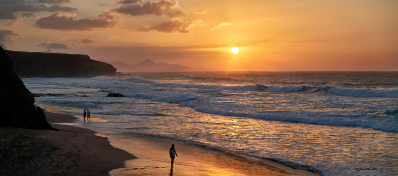 Romantischer Sonnenuntergang am Strand von Fuerteventura Paar spaziert bei Sonnenuntergang am Strand von Fuerteventura entlang