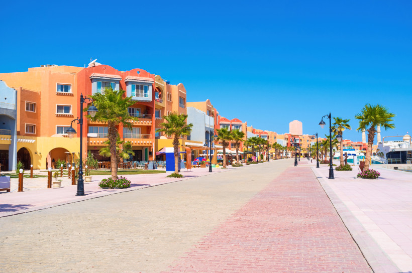 Lebhafte Marina-Promenade mit farbenfrohen Gebäuden, Palmen und Restaurants bei strahlend blauem Himmel