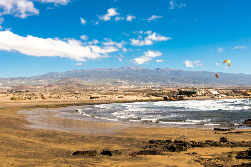Teneriffa - Playa de Leocadio Machado langer Naturstrand mit goldbraunem Sand, Wellen, Dünenlandschaft und Kitesurfern am Himmel.