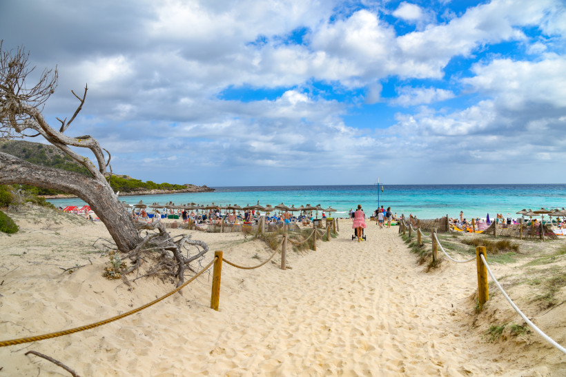 Familien am feinsandigen Strand von Cala Ratjada auf Mallorca mit türkisblauem Meer – ideales Reiseziel für einen entspannten Familienurlaub.
