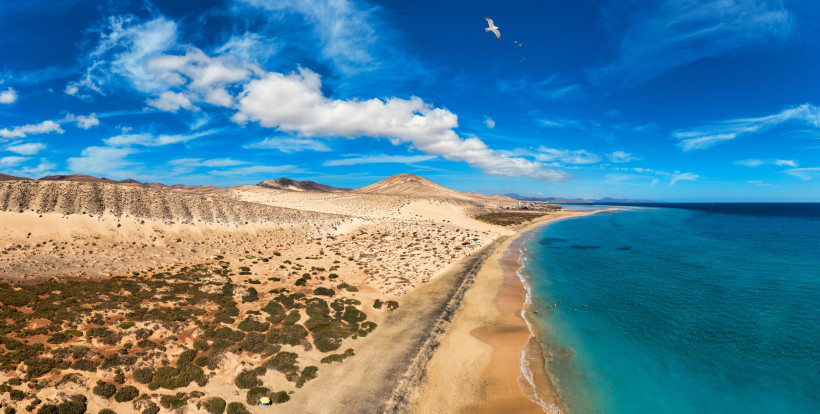 Küstenlandschaft mit Sandstrand, Dünen und Blick auf den Atlantik unter blauem Himmel