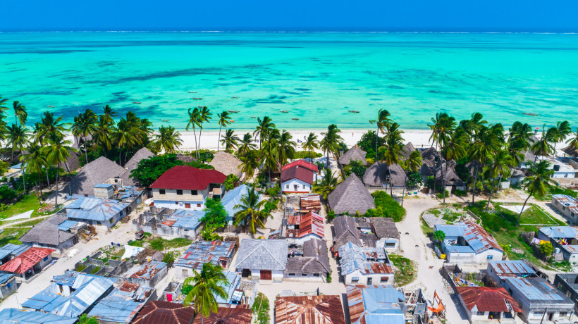 Sansibar - Jambiani Blick auf ein traditionelles Dorf auf Sansibar mit Palmen, Häusern und Hütten direkt am weißen Sandstrand mit türkisblauem Meer