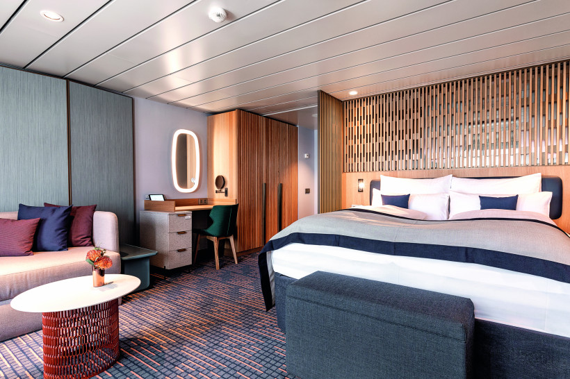 Schlafbereich der Schöne Aussicht Suite auf Mein Schiff 1 mit Doppelbett, Sitzgruppe und Schreibtisch