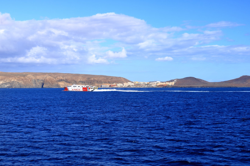 Fähre auf dem Meer vor der Küste von Callao Salvaje mit Bergen und Siedlung im Hintergrund