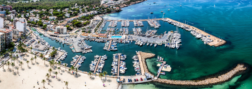 Luftaufnahme des Yachthafens von El Arenal mit zahlreichen Segelbooten und Stegen an der Küste.