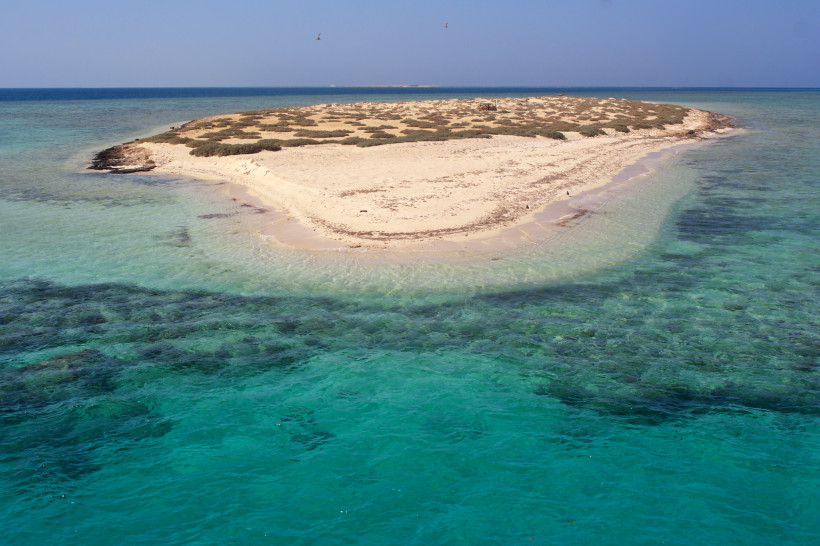 Unberührte Sandinsel im Roten Meer mit türkisfarbenem Wasser und wilder Vegetation