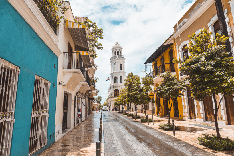 Santo Domingo, Dom.Rep. Koloniale Altstadtstraße in Santo Domingo mit bunten Häusern und Blick auf einen weißen Uhrturm, Dominikanische Republik