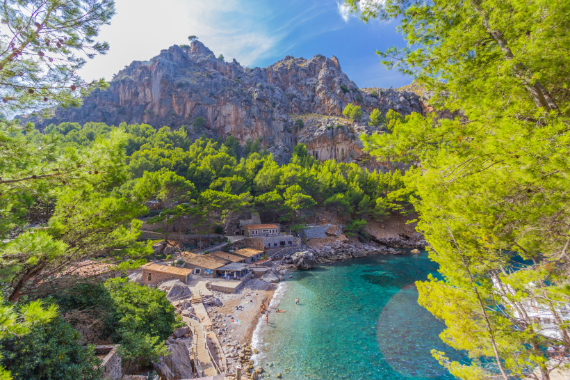 Bucht von Sa Calobra mit Kiesstrand, türkisfarbenem Wasser, Pinienwald und steilen Felswänden